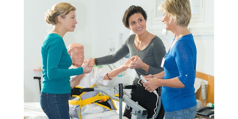 two nursing students learning patient transport techniques from an instructor