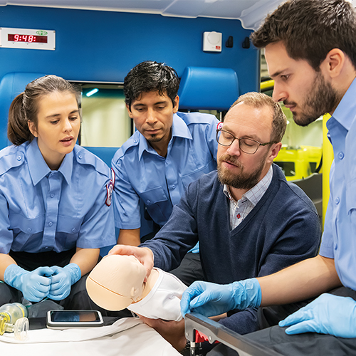 instructor showing infant manikin features to paramedic students