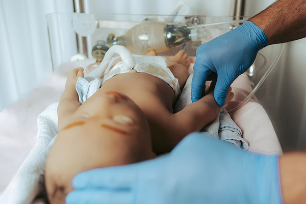 healthcare worker checking pulse of neonatal simulator