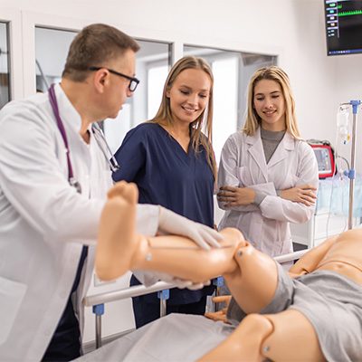 man showing nursing students a manikin in a sim lab