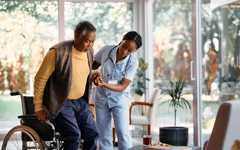 nurse helping elderly man out of a wheelchair