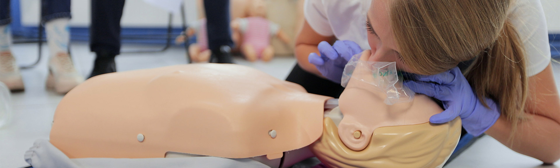 CPR Instructor teaching with Laerdal Little Anne CPR manikin in a class