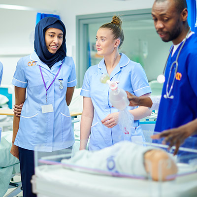 Nursing instructor and students with infant manikin